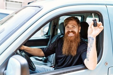 Young irish man smiling happy sitting on the car holding key at the city.