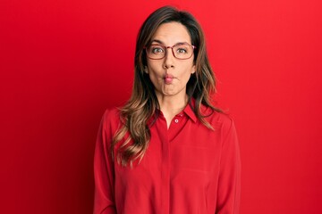 Poster - Young latin woman wearing casual clothes and glasses making fish face with lips, crazy and comical gesture. funny expression.