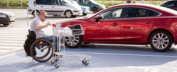  Person with a physical disability pushes a cart towards a car in a supermarket parking lot