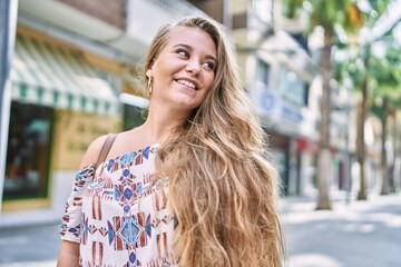 Wall Mural - Young blonde girl smiling happy standing at the city.