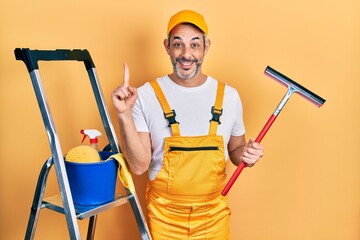 Poster - Handsome middle age man with grey hair wearing glass cleaner uniform and squeegee smiling with an idea or question pointing finger with happy face, number one