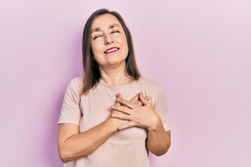 Canvas Print - Middle age hispanic woman wearing casual clothes smiling with hands on chest with closed eyes and grateful gesture on face. health concept.