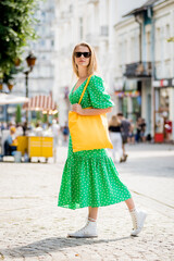 Canvas Print - Young beautyful woman with yellow linen eco bag on city background.