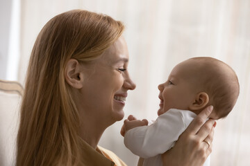 profile side view smiling loving young mother playing with baby close up, happy caucasian mom and li