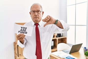 Sticker - Senior business man holding you are fired banner at the office with angry face, negative sign showing dislike with thumbs down, rejection concept