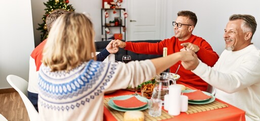 Sticker - Group of middle age caucasian family having christmas dinner and praying for food sitting on the table at home.