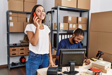 Canvas Print - Man and woman business partners talking on the smartphone and writing on clipboard at storehouse