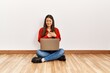 © Krakenimages.com - Young brunette woman sitting on the floor at empty room with laptop smiling with hands on chest with closed eyes and grateful gesture on face. health concept.