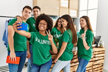 Group of young volunteers smiing happy make selfie by the smartphone standing at charity center.