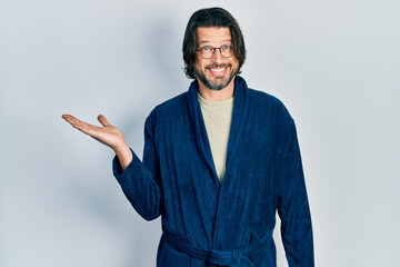 Sticker - Middle age caucasian man wearing bathrobe and glasses smiling cheerful presenting and pointing with palm of hand looking at the camera.