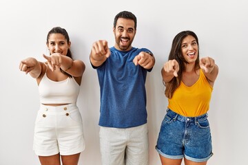 Group of young hispanic people standing over isolated background pointing to you and the camera with fingers, smiling positive and cheerful