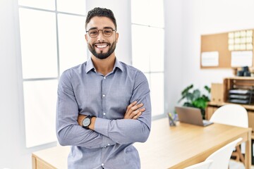 Wall Mural - Young arab man smiling confident standing with arms crossed gesture at office