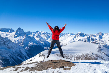 Freedom concept, girl looks at snowy mountains on blue sky background