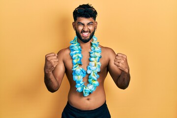 Canvas Print - Arab man with beard wearing swimsuit and hawaiian lei screaming proud, celebrating victory and success very excited with raised arms