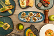Set of international food dishes of fish, grilled salmon, Norwegian salmon blinis, red tuna tataki, hake in sauce, tartare, limes, forks and pepper