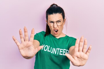 Canvas Print - Young hispanic woman wearing volunteer t shirt doing stop gesture with hands palms, angry and frustration expression