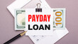 © Елена Дигилевич - On a gray background, a white calculator, a pen, banknotes and a sheet of paper under a black paper clip with the text PAYDAY LOAN. Business concept