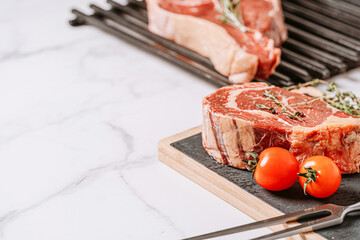 Wall Mural - three delicious steaks ready to grill on a white marble surface