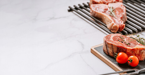 Wall Mural - three delicious steaks ready to grill on a white marble surface