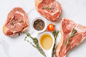 Wall Mural - three delicious steaks ready to grill on a white marble surface