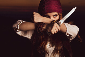 Wall Mural - Outdoor portrait of young female in pirate costume with a knife