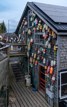 Bernard, ME - USA - Oct.15,2021: Vertical View Of An Old Wooded Shingled Workshop, Covered With Lobster Buoys, Traps And Other Marine Tools. Located Along The Bass Harbor In Mount Desert Island.