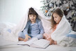 © alexkich - A family with children having fun on the bed under the covers during the Christmas holidays.