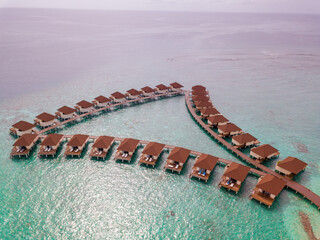 Wall Mural - Aerial view from the drone of bungalows on the water, tourist village in maldives.