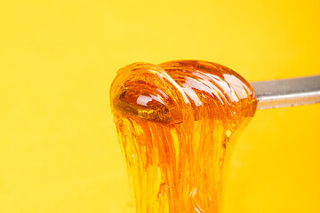 Wall Mural - amber yellow cannabis wax concentrate dripping from the dabbing tool close-up