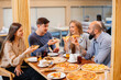 © Andrii - A group of young cheerful friends is sitting in a cafe talking and eating pizza. Lunch at the pizzeria.