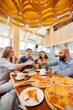 © Andrii - A group of young cheerful friends is sitting in a cafe talking and eating pizza. Lunch at the pizzeria.