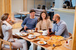 © Andrii - A group of young cheerful friends is sitting in a cafe talking and eating pizza. Lunch at the pizzeria.