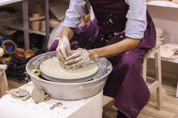 Pottery workshop. Closeup of woman artist hands molding clay on pottery wheel. Creative handmade craft. Ceramic art studio.