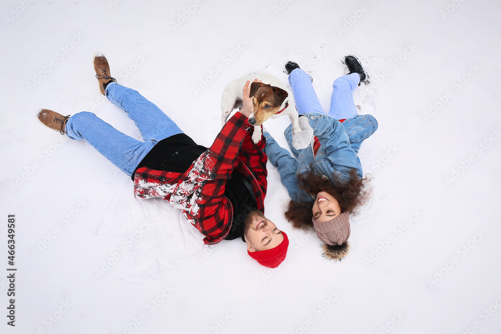 Happy young couple with dog in forest on winter day