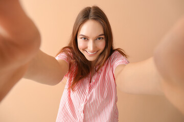 Canvas Print - Happy young woman taking selfie on beige background