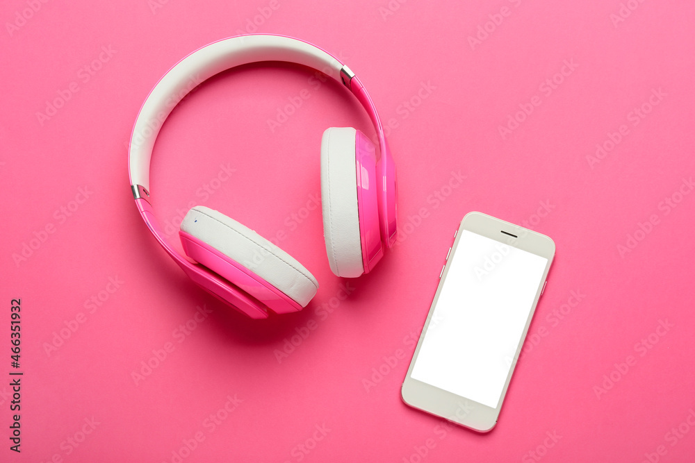 Modern headphones and mobile phone on pink background