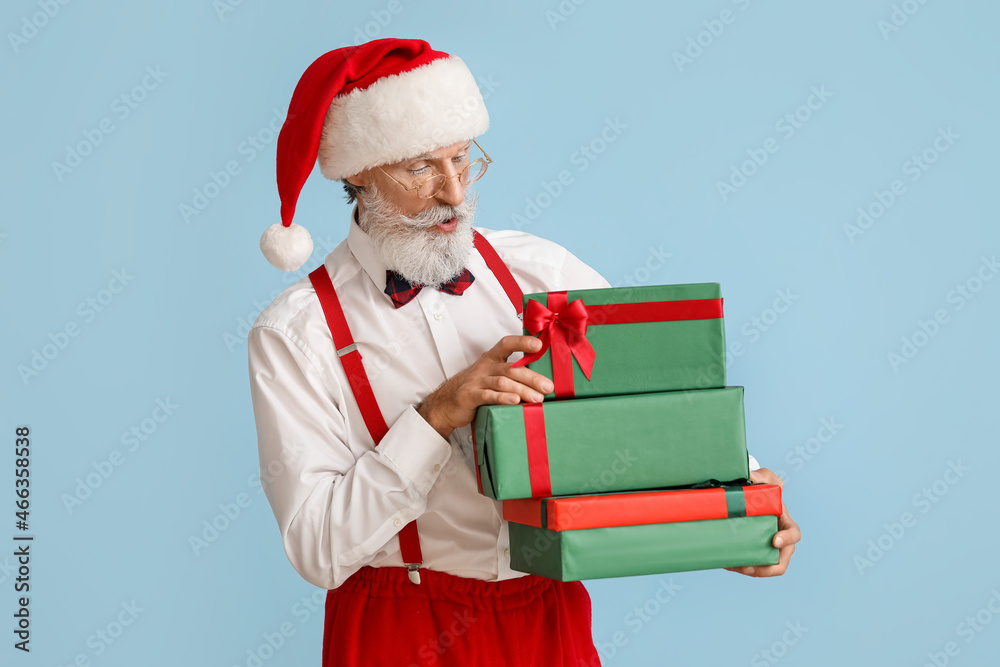Santa Claus with gifts on color background