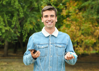 Poster - Young man with phone and power bank outdoors