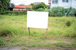 Blank white empty mockup template of a real estate sign at front of a lot of vacant lan