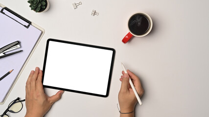 Above view man holding stylus pen and using digital tablet on white office desk.