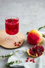 Wall Mural - Pomegranate juice in a wooden dish with pomegranate seed with grey  background and a napkin decoration  , for food adverting , front view , green leaf