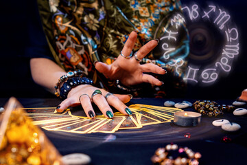 Wall Mural - A witch spread out her tarot cards on the table. Hands close-up. The zodiac circle in the upper right corner. The concept of divination and astrology