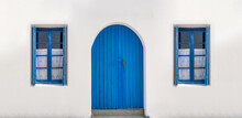 Blue Wooden Door On Whitewashed Wall Windows With Opened Shutters And Curtains Background.