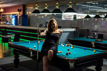 Wall Mural - beautiful young woman is sitting on the snooker table