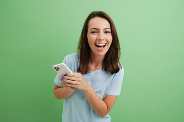 Wall Mural - Young brunette woman laughing while using cellphone