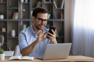 Wall Mural - happy handsome young man in eyewear looking at cellphone screen, reading message, or email, communic