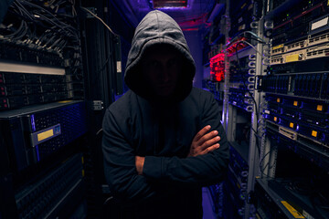 Wall Mural - Gloomy man standing between racks with computer equipment