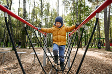Boy Walking On Play Equipment At Park During Autumn