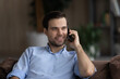 © fizkes - Happy millennial generation man talking chatting on cellphone with friends, discussing life news with family, making order in internet store speaking with operator, resting on cozy couch at home.