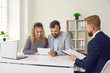 © Studio Romantic - Clients reading contract. Happy young married couple reading contract terms and conditions sitting at office desk during meeting with realtor, real estate agent, insurance broker or mortgage advisor